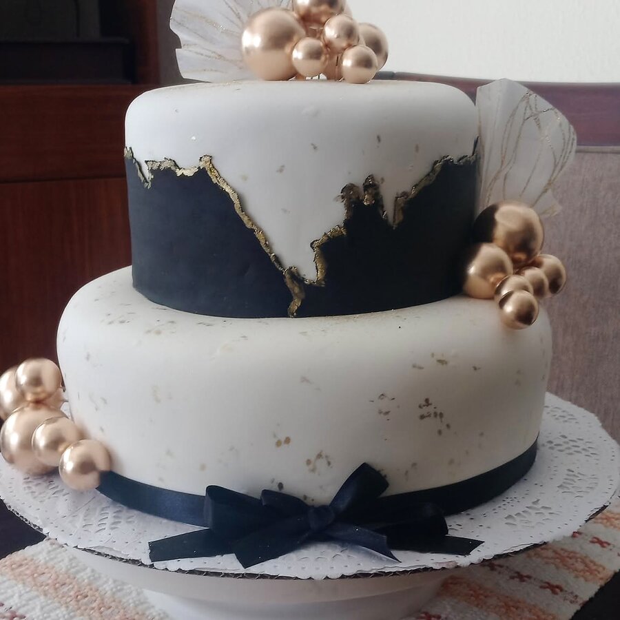 Pastel real de dos pisos blanco y azul marino con perlas doradas y moño